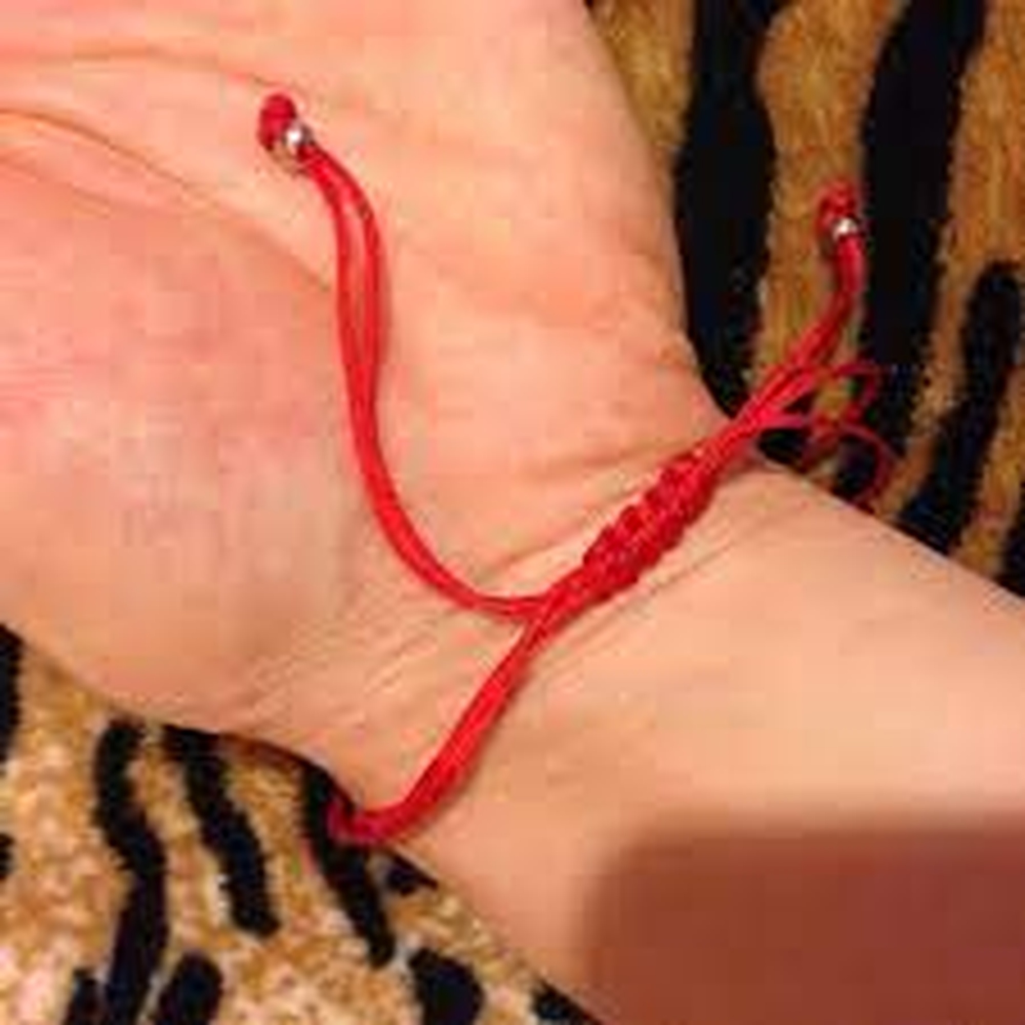 Завязанные нитки на руке. Красная шерстяная нить. Красная нить на руке.